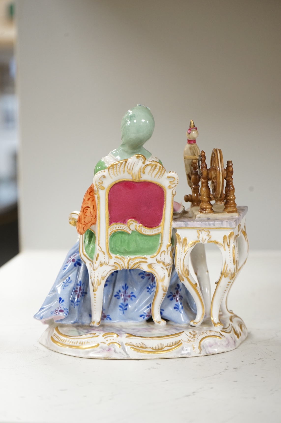 A Meissen style figure of a seated lady at her spinning wheel, 15.5cm high.